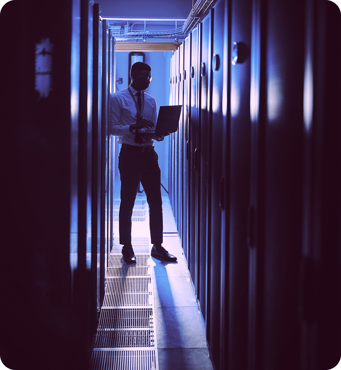 Person working with laptop in server room.